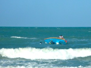 Two men trying to right an upturned jangada