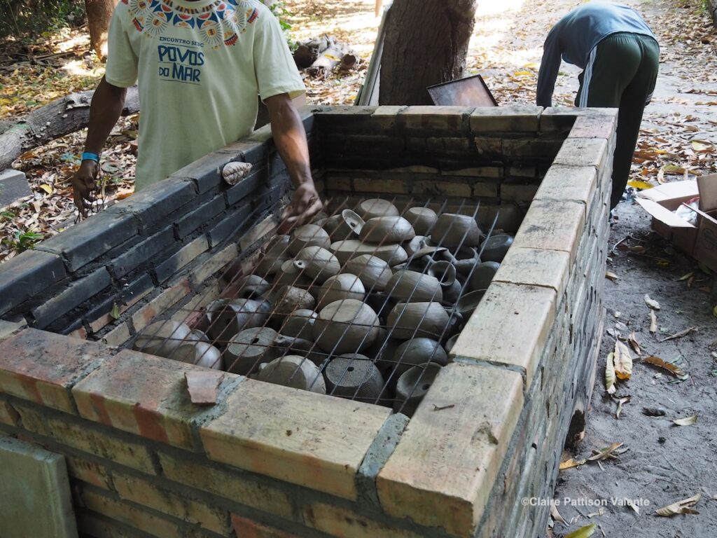 a rudimentary kiln in the woods, filled with clay pots about to be fired