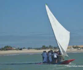 Grupo de pessoas e padres navegando em uma jangada no dia de São Pedro, Prainha do Canto Verde.